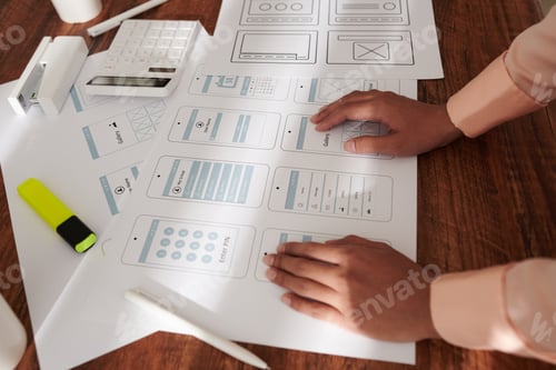 Preview: UX Designer Leaning on Table with Layouts