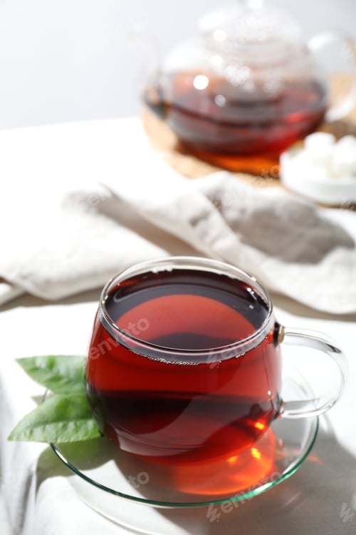 Preview: Refreshing black tea in cup on light table, closeup