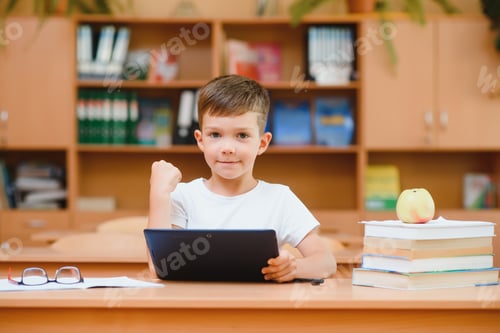 Visualização: Aluno do ensino fundamental usando tablet digital com colega estudando em segundo plano na sala de aula