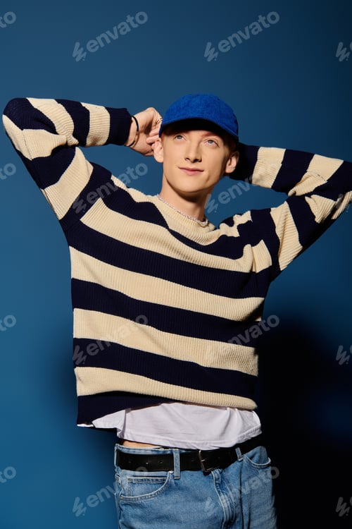 Preview: Emotional expression of a young man in striped sweater posing against a blue backdrop