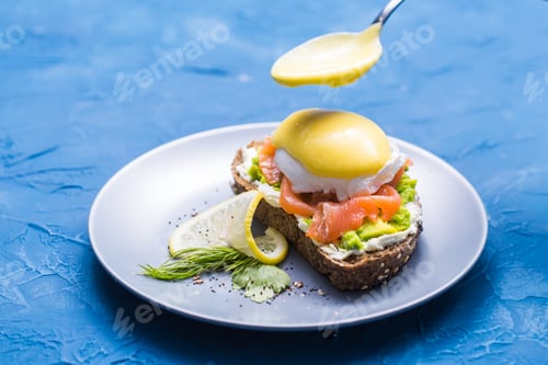 Preview: Morning and breakfast concept - Preparation of sandwich with salmon, spoon is pouring sauce on it