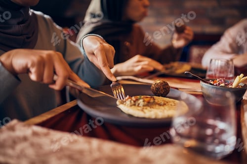 Preview: Close-up of Arab woman eating during family meal at dining table.