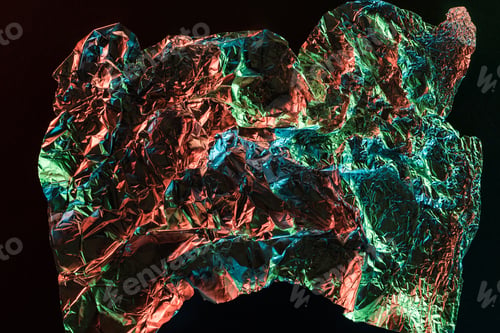 Preview: top view of shiny crumpled foil with colorful lighting reflection in darkness isolated on black