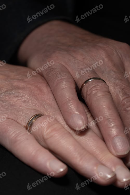 Preview: The hands of a mature, newly married couple showing off their rings.