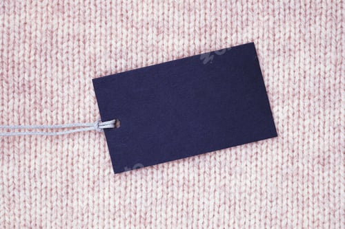 Preview: Blank paper label on knitted wool clothes background