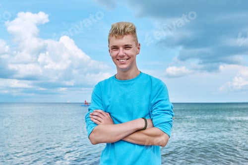 Preview: Portrait of smiling young guy outdoor, on sea beach