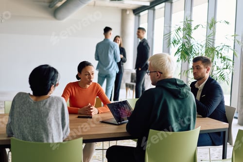 Preview: A diverse team of business professionals engaged in a discussion around a conference table in an