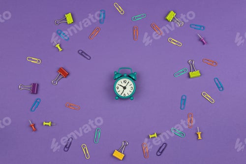 Preview: Small alarm clock on purple background with stationery items