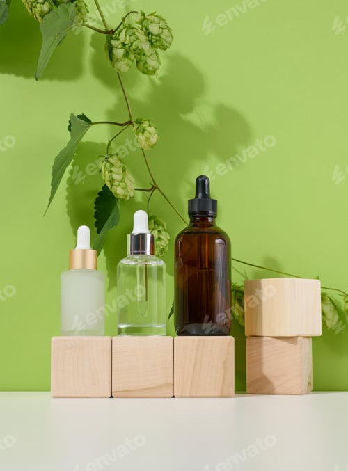 Preview: Three glass bottles with pipettes for cosmetics, acids, oils on a green background. Empty containers