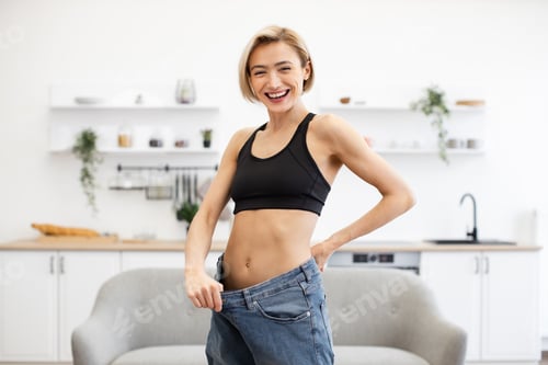 Preview: Happy woman showing dramatic weight loss in oversized jeans