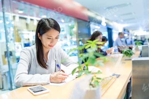Preview: Woman study on the note with her cellphone in university