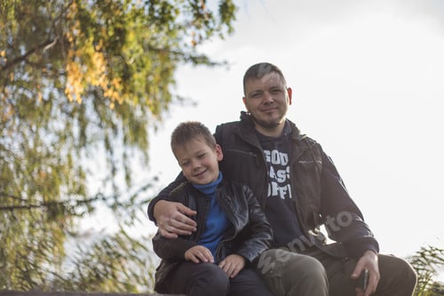 Preview: Father hugging his son outdoors on the bench. Precious moments between Dad and son