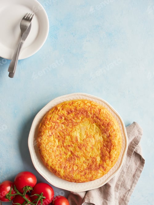Preview: Homemade potato omelette, typical Spanish food called tortilla de patatas, with fresh red tomatoes.