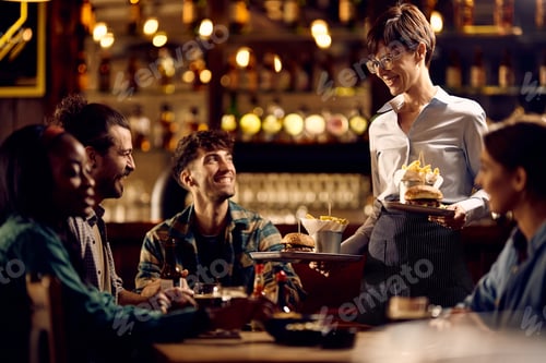 Preview: Happy waitress bringing French fries and burgers to pub customers.