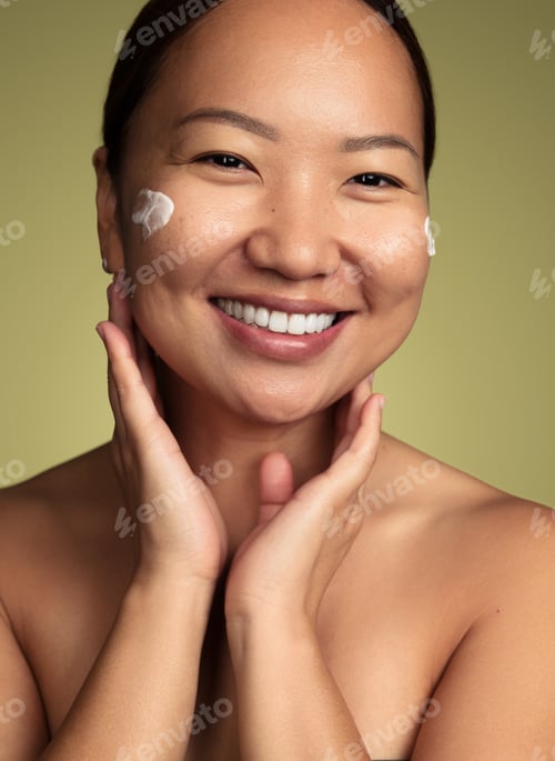 Preview: Merry Asian woman with cream on cheeks