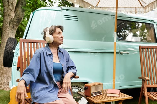 Preview: Senior woman enjoying a peaceful afternoon in a lush garden near a vintage van