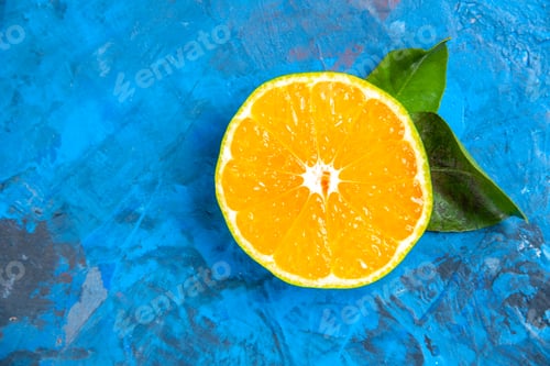 Preview: top view cut orange on blue background with free space