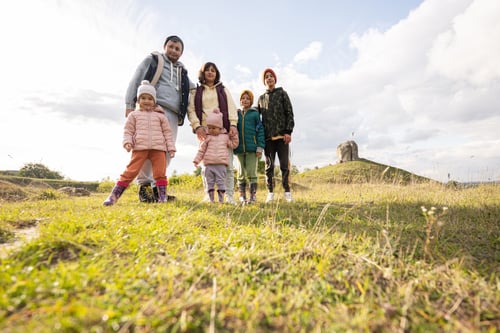 Preview: Family exploring nature. Children with parents stand against big stone in hill. Pidkamin, Ukraine.