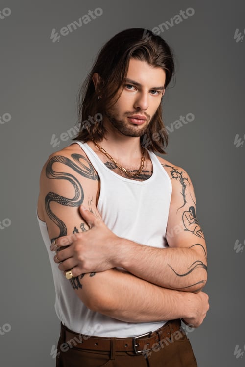 Preview: Fashionable and tattooed man in tank top posing isolated on grey