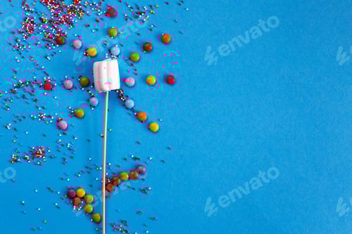 Preview: marshmallows composition on wooden skewers on blue background.
