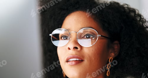 Preview: Businesswoman with trendy glasses reading information on a computer screen while working in an offi