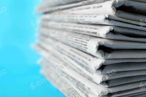 Preview: Stack of newspapers on light blue background, closeup. Journalist's work