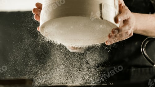 Preview: Male hands of a cook sifting flour through a sieve in the kitchen
