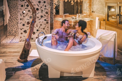 Preview: Happy interracial couple relaxed in the jacuzzi enjoying their self and drinking wine