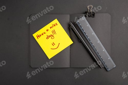 Preview: top view black notepad have a nice day written on note paper ruler pen binder clip on dark