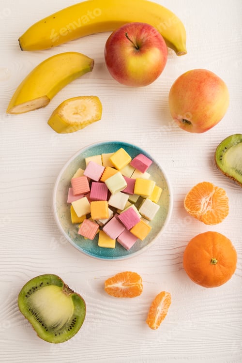 Preview: Various fruit jelly chewing candies on white wooden. apple, banana, tangerine, top view.