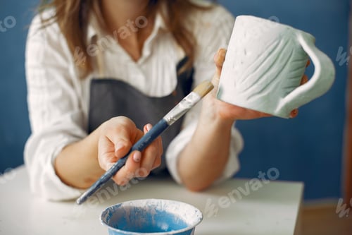 Preview: A young woman mpainting dishes in a pottery