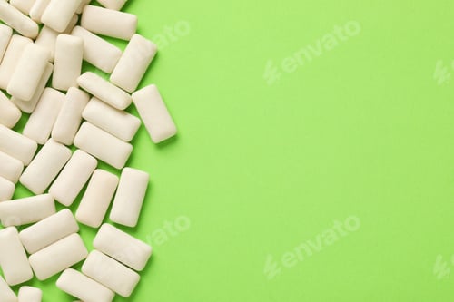 Preview: Many chewing gum pieces on green background, flat lay. Space for text