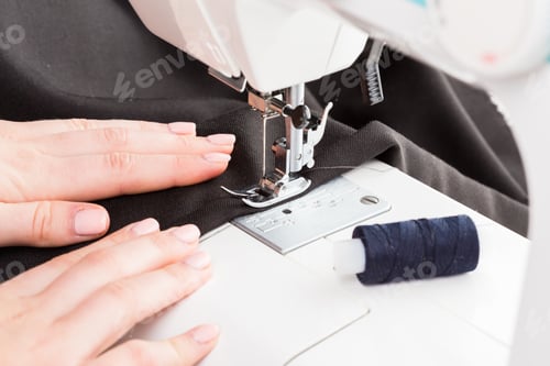 Preview: Sewing machine in use showing hands guiding fabric and thread