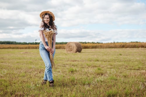 Preview: Beautiful woman in nature in a field with haystacks. life in the country