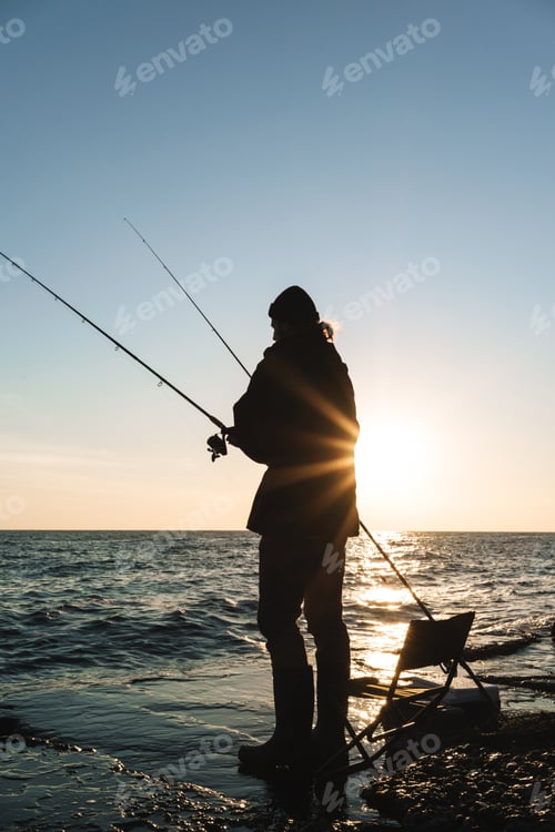 Preview: Silhouette of man fisherman wearing coat, holding rod