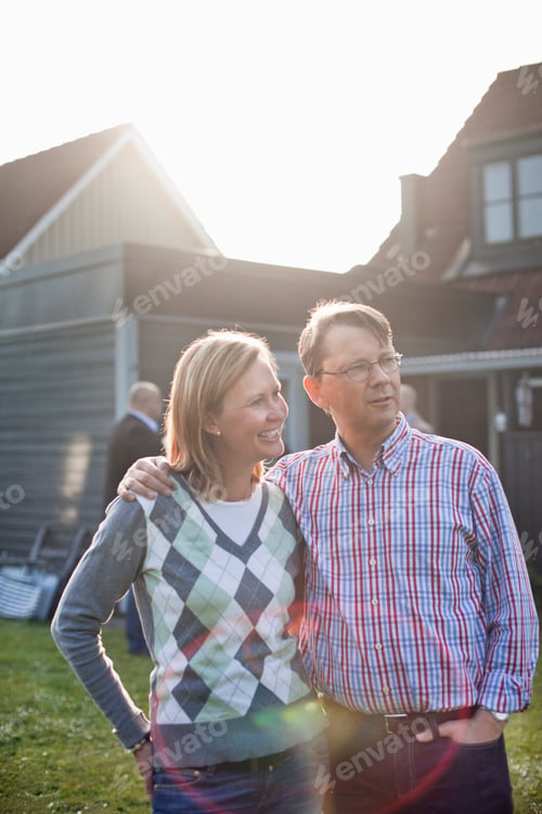 Preview: Man standing with arm around woman against house on sunny day