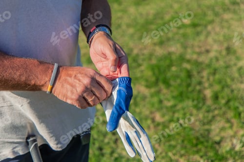 Preview: closeup of senior golfer adjusting glove before starting golf game