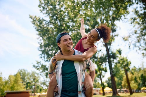 Preview: Young playful couple piggybacking in the park.