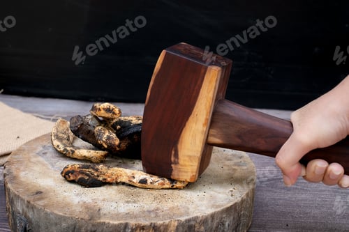 Preview: Hand Holding a Wooden Mallet Crushing Food