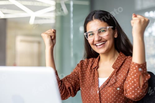 Preview: Young woman celebrating success looking at laptop