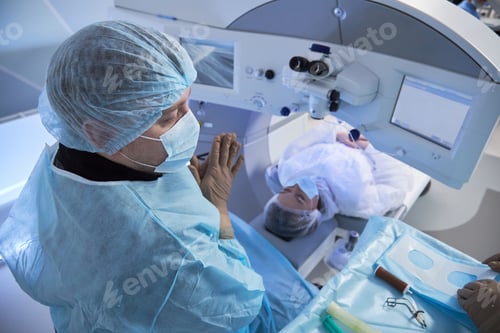 Preview: Middle Aged Male Surgeon Performing Eye Surgery on Young Adult Woman