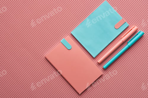 Preview: top view of pens and notebooks on textured pink