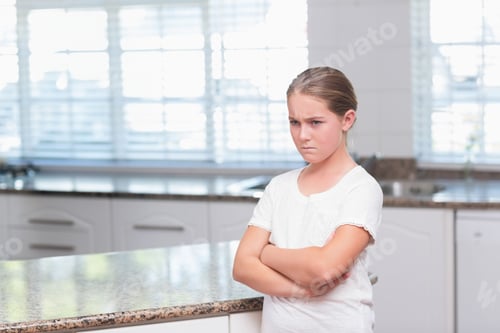 Preview: Woman leaning against granite countertop in modern kitchen, frowning with crossed arms, copy space
