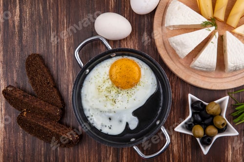 Preview: top view fried eggs in a frying pan with olives and green onions black bread