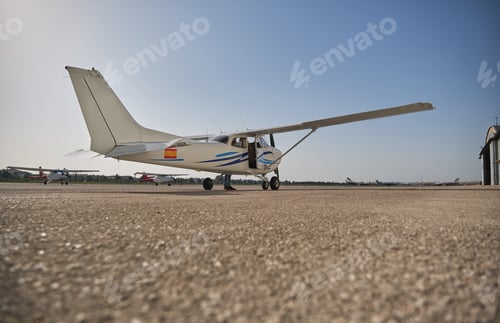 Preview: White high wing aircraft parked on runway under blue sky