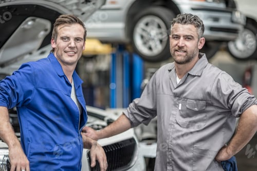 Preview: Two confident car mechanics in repair garage