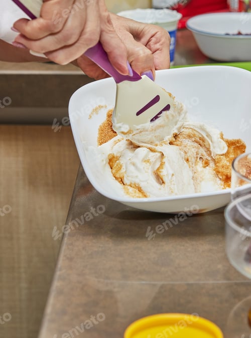 Preview: Person preparing creamy dessert with a plastic spoon in the kitchen