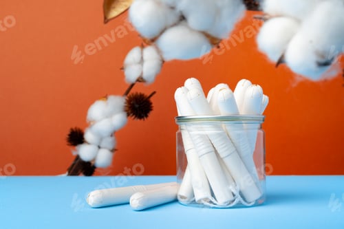Preview: Female medical tampons and cotton flower on blue paper background