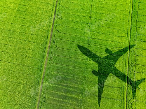 Preview: Shadow airplane flying above green field. Sustainable fuel. Biofuel in aviation. Sustainable