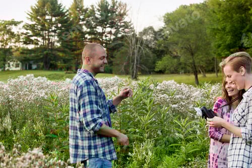 Preview: Three people in a wildflower meadow, one with a camera